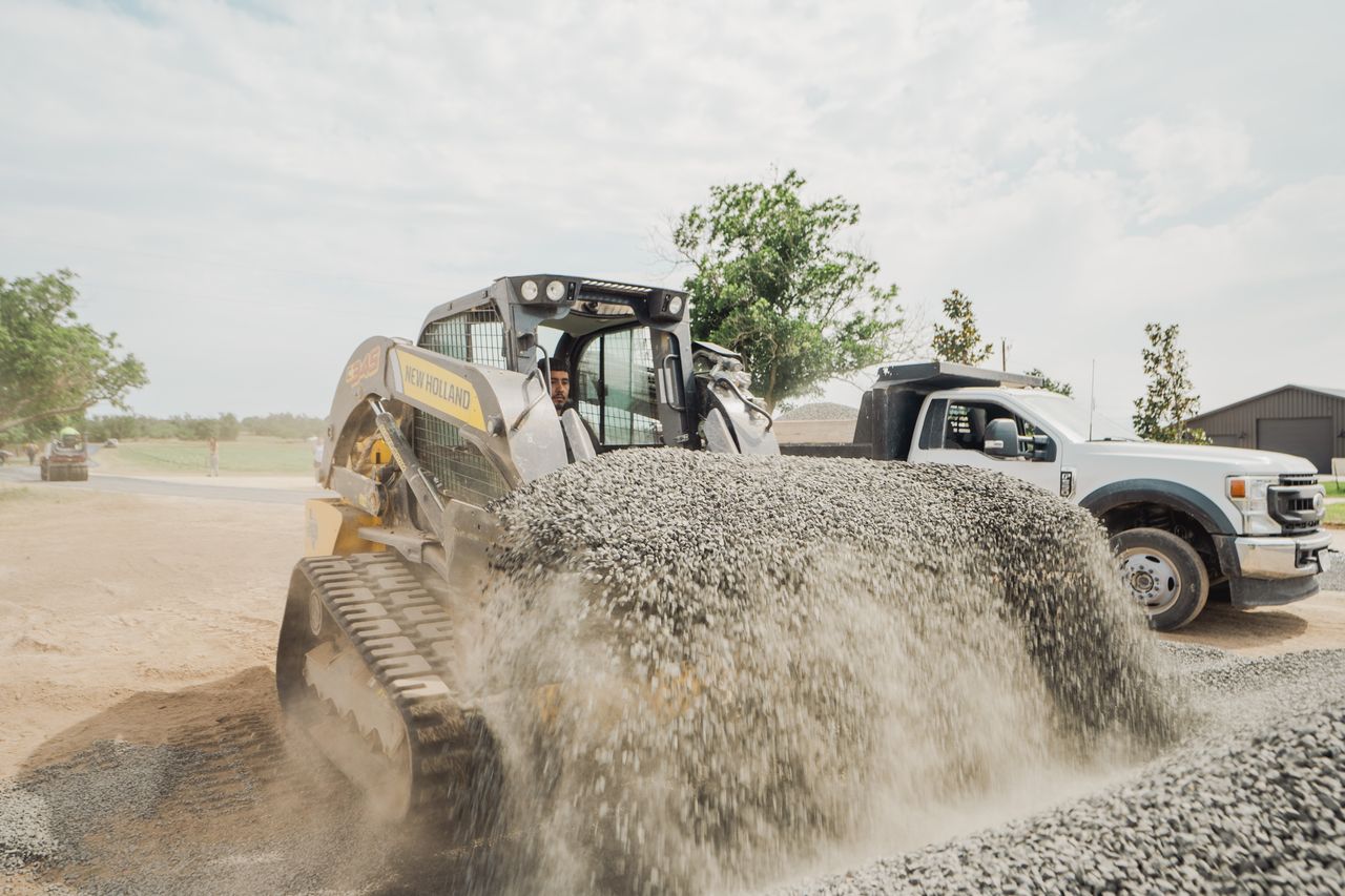 Skid-steer handling aggregate at a road project