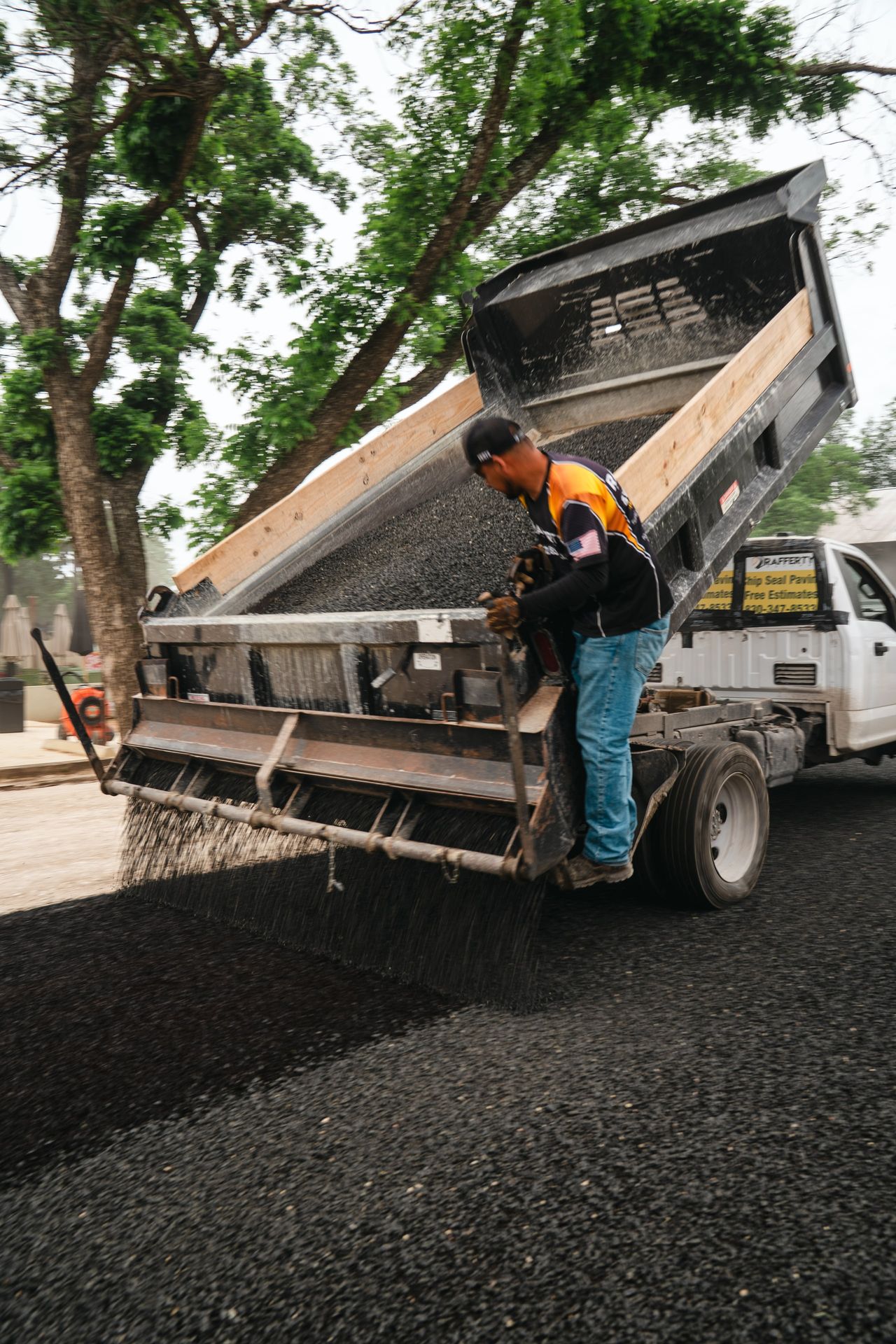 Aggregate dropping from a spreader truck during paving work