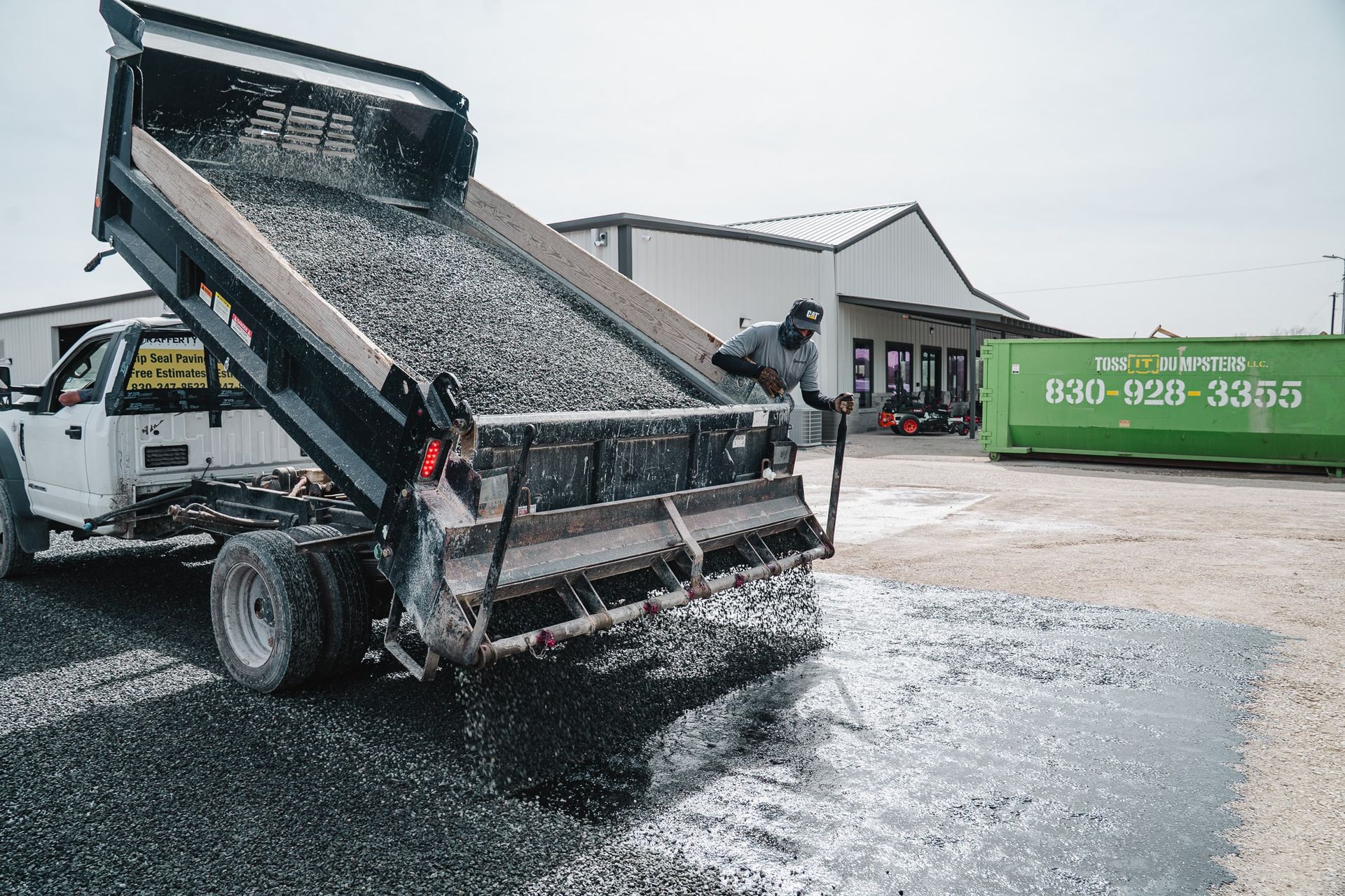 Aggregate spreader placing stone during chip-seal work