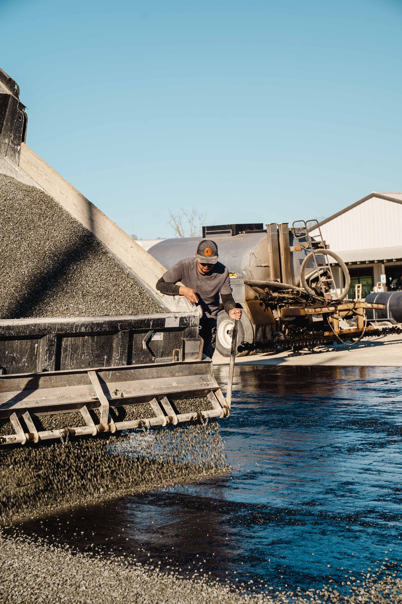 Crew working beside aggregate-spreading equipment