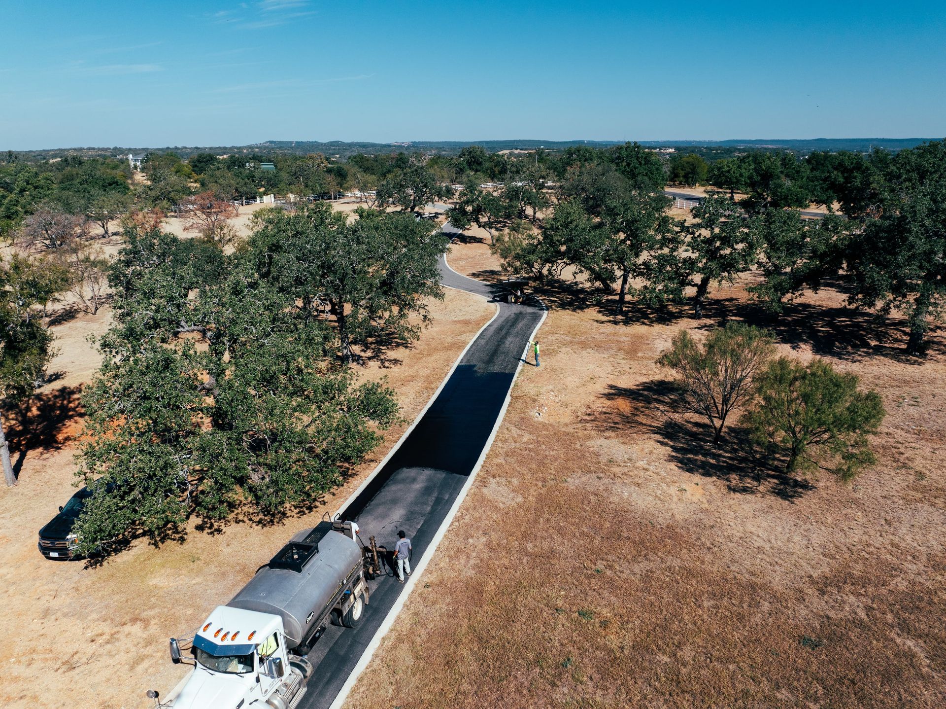 Aerial view of a distributor applying binder along a private road