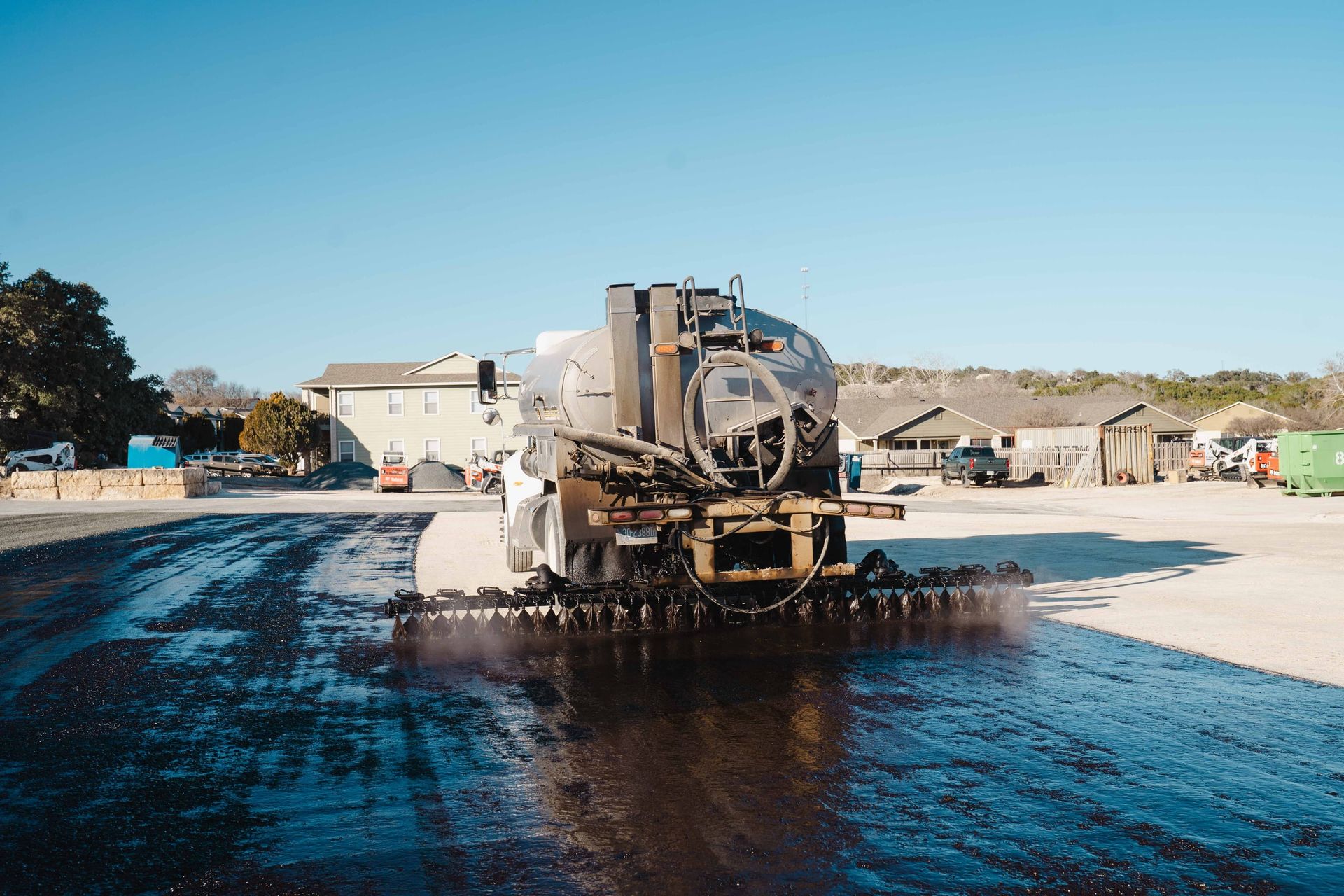 Distributor truck applying binder before aggregate placement