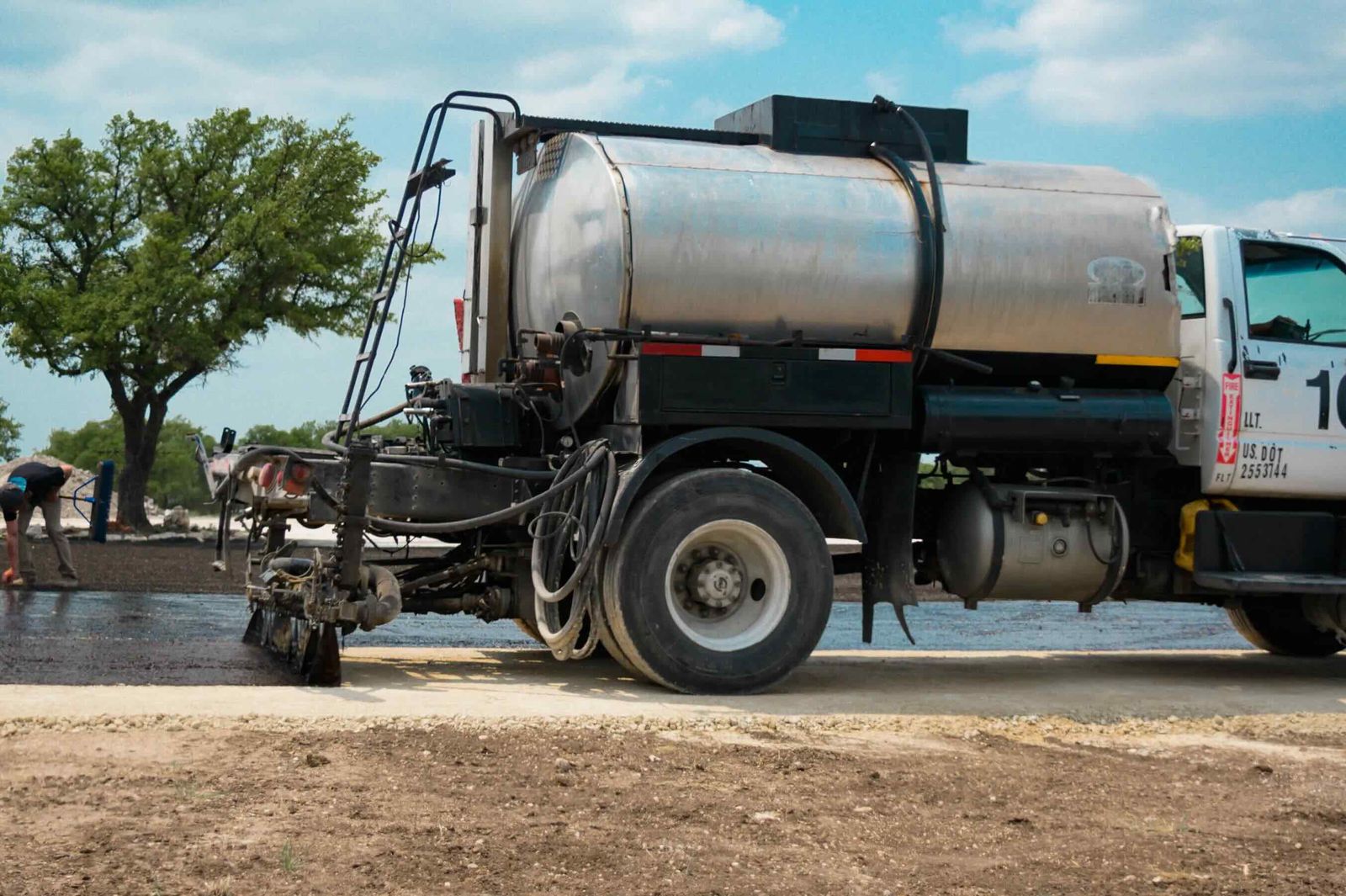 Material being applied from a distributor truck during chip-seal work
