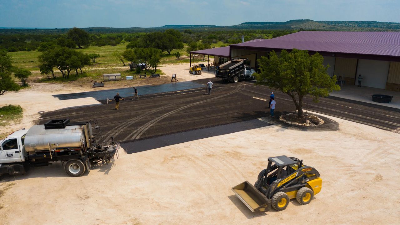 Aerial view of active chip-seal work across a managed-property access area