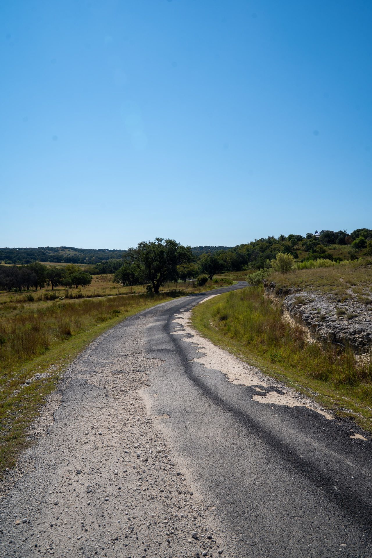 Patchy and deteriorated surface on a curving rural road