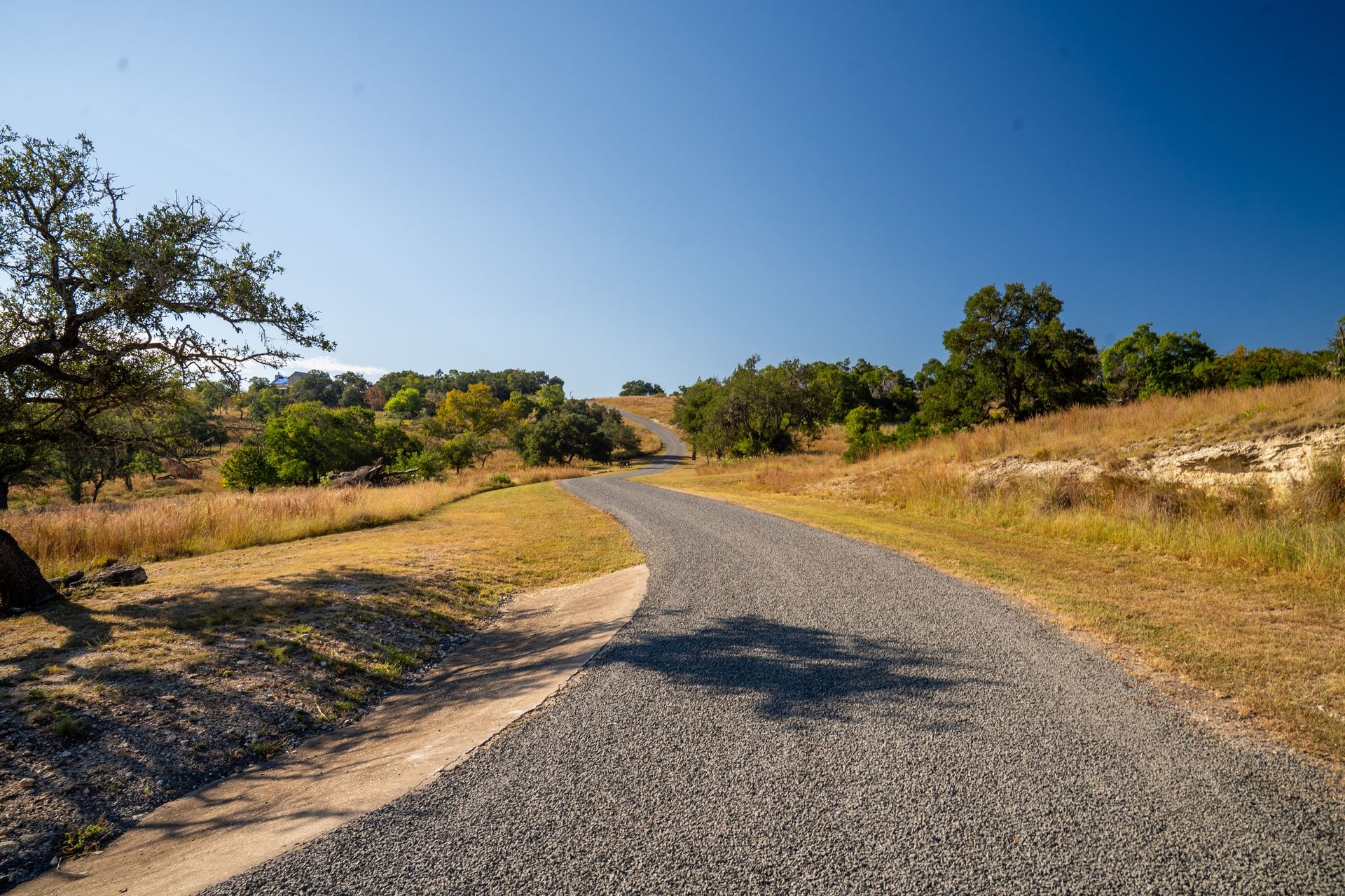 Finished aggregate-surface drive curving through rural land