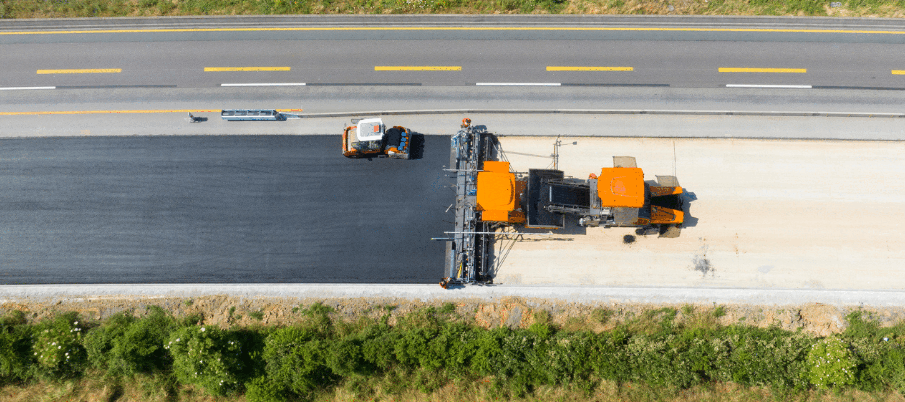 Aerial view of road paving machinery laying asphalt on a highway construction site