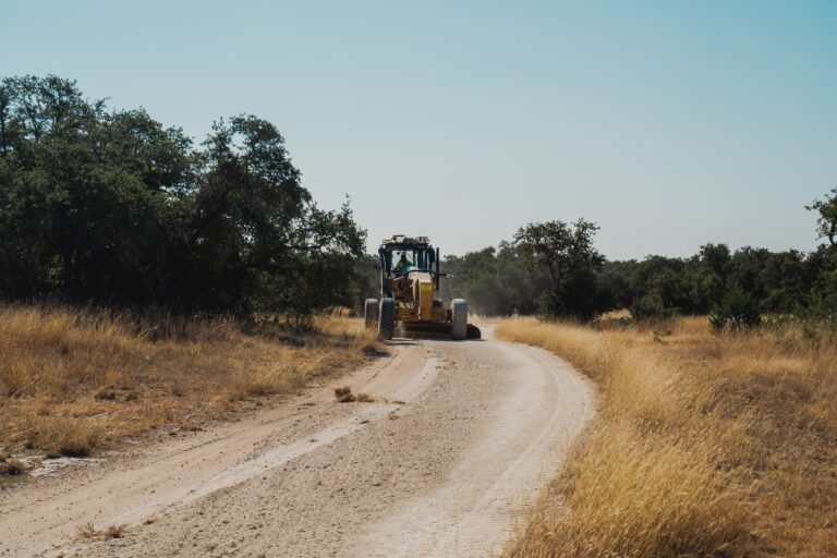 Motor grader grading a caliche road in the Texas Hill Country