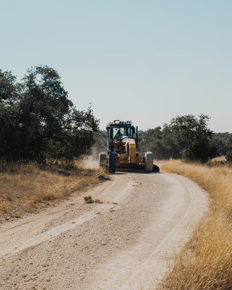 Motor grader grading a caliche road in the Texas Hill Country