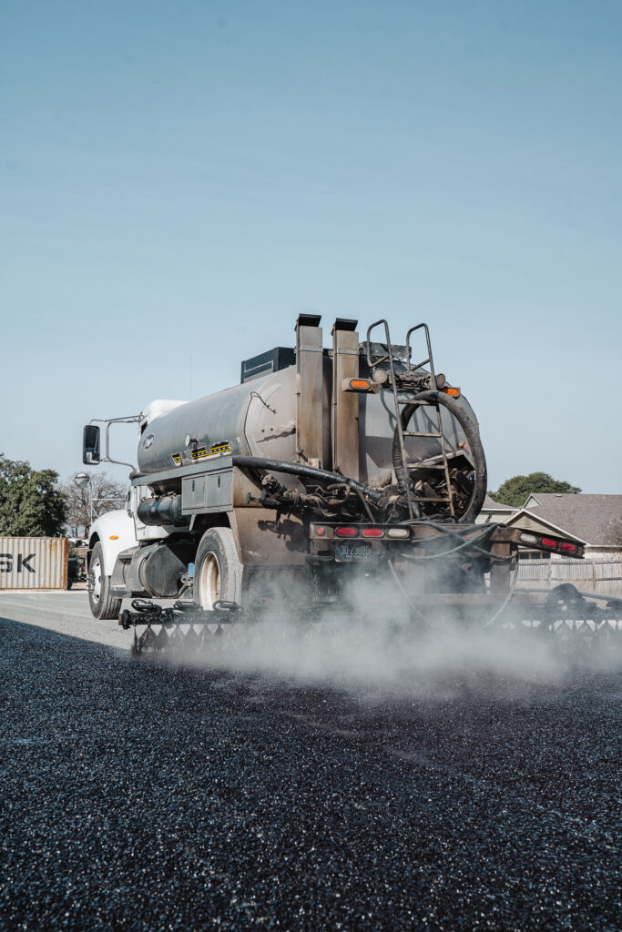 Asphalt paving surface alligatoring from repeated freeze-thaw cycles in Harper, TX: a tandem-axle paving truck spraying