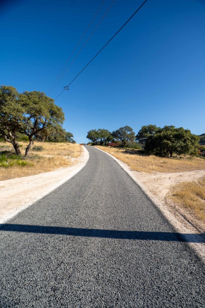 Moisture trapped under seal coating in Lake Medina Shores, TX: a newly paved asphalt road with white concrete shoulders