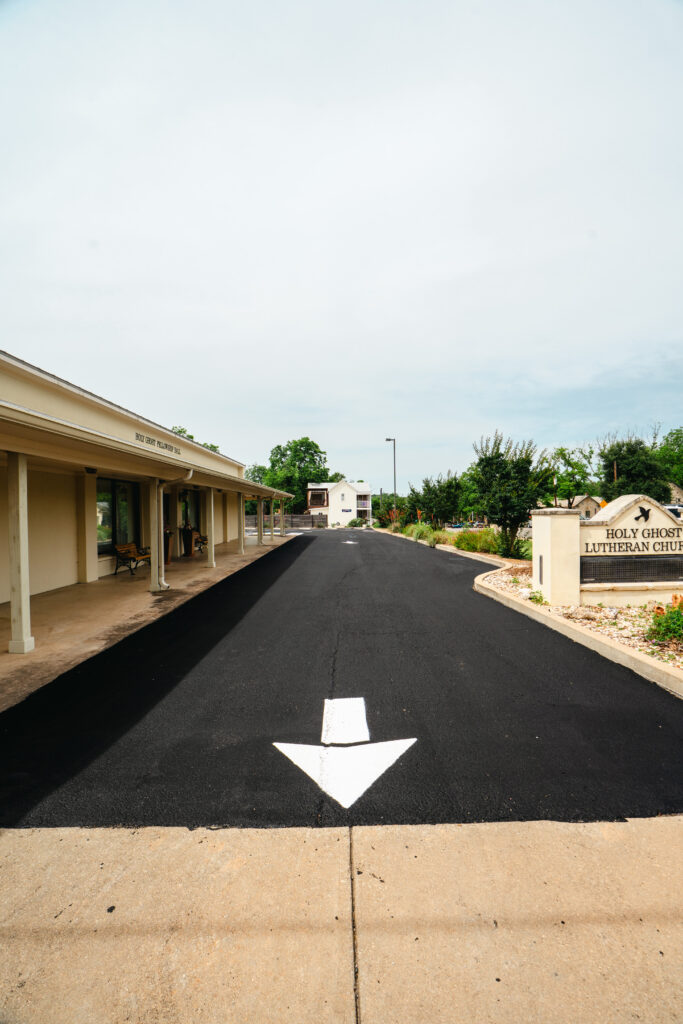 Premature cracking in newly paved driveway in Miles TX: a newly paved asphalt driveway with white directional arrow marking