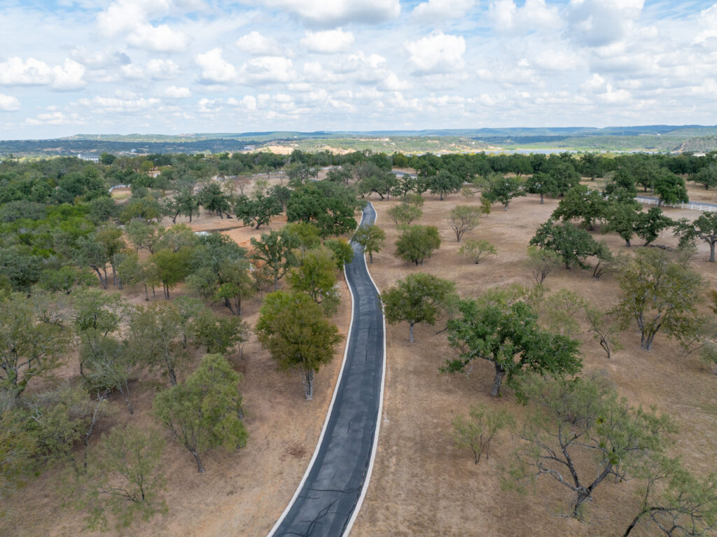 Private road washboarding after heavy rain in Pipe Creek, TX: an aerial view of a newly paved asphalt road cutting through